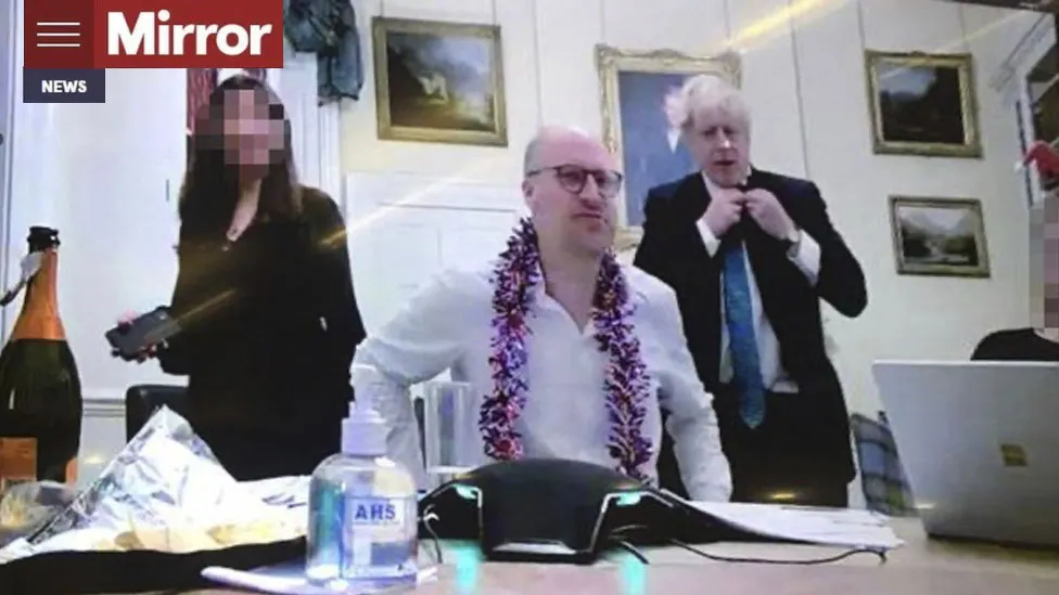 Boris is seen on the right next to a colleague who has tinsel draped over his neck.